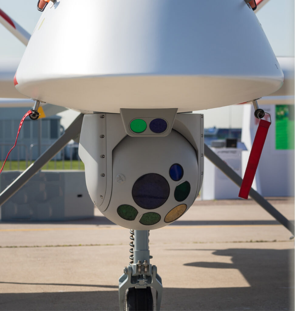 A round aerial camera mounted on the underside of a large drone.